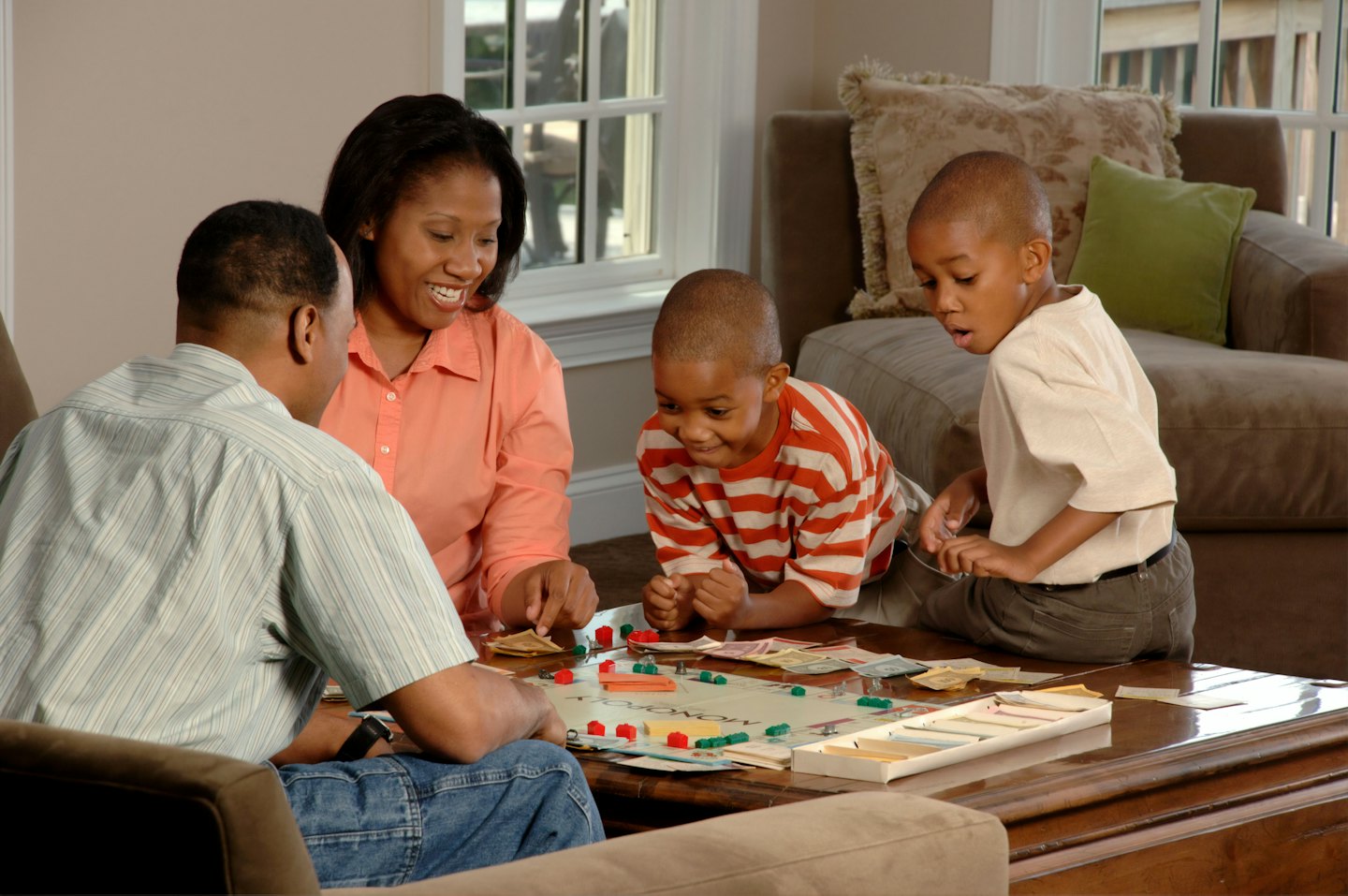 Familie spielt Monopoly am Couchtisch.