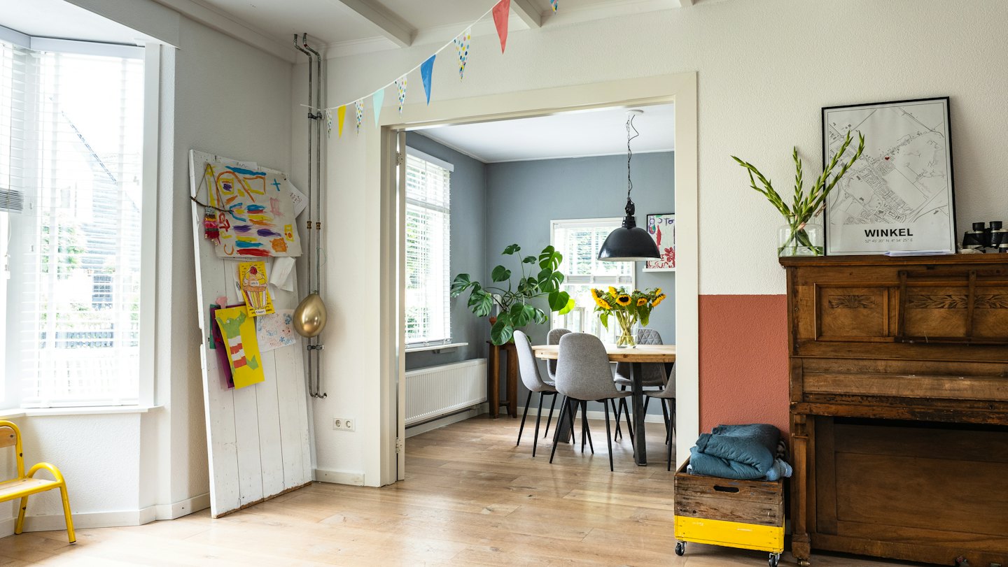 Zwei Räume in einem Haus, einer mit Klavier und Kunst, der andere ein Essbereich.