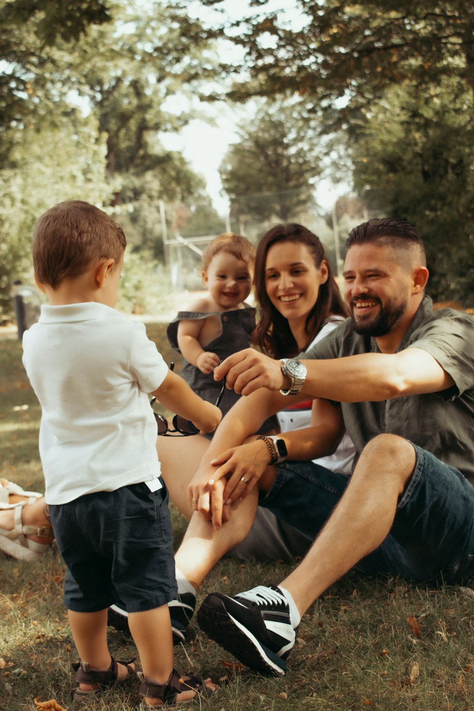 Familie sitzt und spielt zusammen auf dem Rasen im Park.