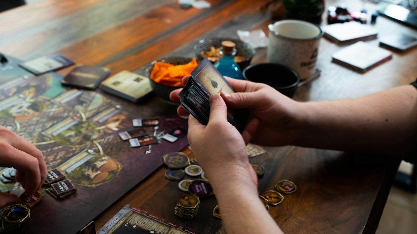 Menschen spielen ein Brettspiel an einem Holztisch.